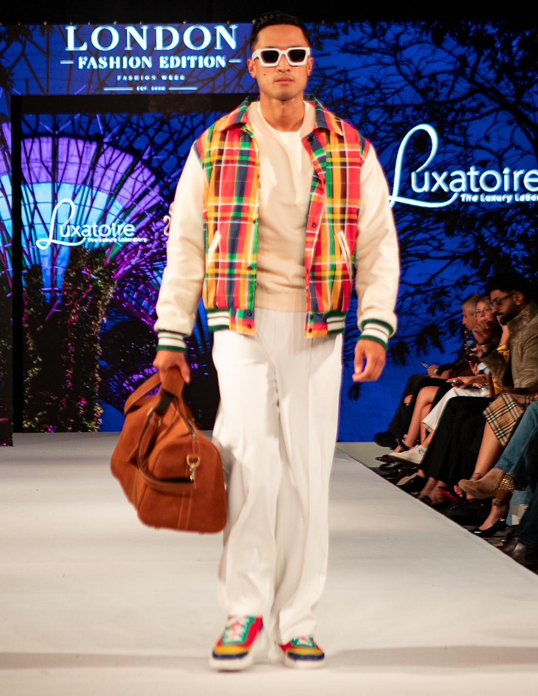 Model wearing a colourful plaid LUXATOIRE menswear design on the London runway