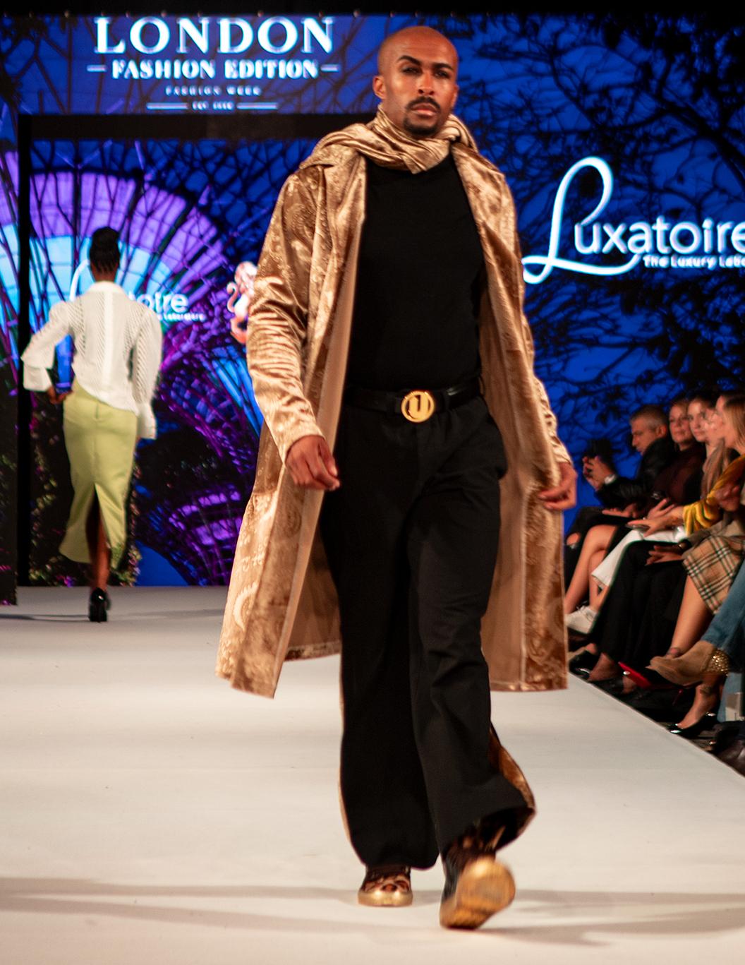 Model wearing a gold and black LUXATOIRE look on the London runway